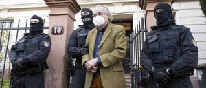 dpatopbilder - 07.12.2022, Hessen, Frankfurt/Main: Bei einer Razzia gegen sogenannte «Reichsbürger» führen vermummte Polizisten, nach der Durchsuchung eines Hauses Heinrich XIII Prinz Reuß (2.v.r.) zu einem Polizeifahrzeug. Die Bundesanwaltschaft hat am Mittwochmorgen mehrere Menschen aus der sogenannten Reichsbürgerszene im Zuge einer Razzia festnehmen lassen. Zahlreiche Beamte seien in mehreren Bundesländern im Einsatz, sagte eine Sprecherin der Karlsruher Behörde . Foto: Boris Roessler/dpa +++ dpa-Bildfunk +++