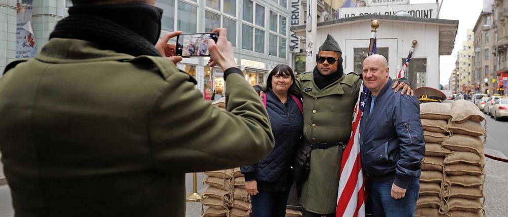 Cheryl und Collin, Touristen aus England, lassen sich am Checkpoint Charlie gemeinsam mit einem Darsteller, der eine US-Uniform trägt, fotografieren.