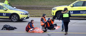 Vier Klimaaktivisten sitzen mit angeklebten Händen auf dem Zubringer einer Start-und Landebahn am Airport Franz-Josef-Strauß.