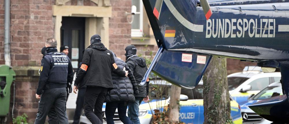 Eine Person (2.v.r.) wird von Polizisten aus einem Hubschrauber gebracht. Die Bundesanwaltschaft hat am Mittwochmorgen mehrere Menschen aus der sogenannten "Reichsbürgerszene" im Zuge einer Razzia festnehmen lassen. Zahlreiche Beamte waren in mehreren Bundesländern im Einsatz, sagte eine Sprecherin der Karlsruher Behörde. Beim Bundesgerichtshof in Karlsruhe sollen die Haftprüfungen stattfinden.