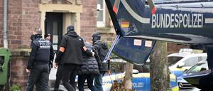 Eine Person (2.v.r.) wird von Polizisten aus einem Hubschrauber gebracht. Die Bundesanwaltschaft hat am Mittwochmorgen mehrere Menschen aus der sogenannten "Reichsbürgerszene" im Zuge einer Razzia festnehmen lassen. Zahlreiche Beamte waren in mehreren Bundesländern im Einsatz, sagte eine Sprecherin der Karlsruher Behörde. Beim Bundesgerichtshof in Karlsruhe sollen die Haftprüfungen stattfinden.