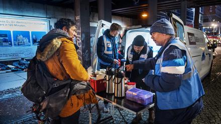 Andre Ruschkowski, Marian, 19 und Michael, 39 verteilen Essen, bei der Suppenbus-Tour von Hertha BSC Fans am Alexanderplatz.