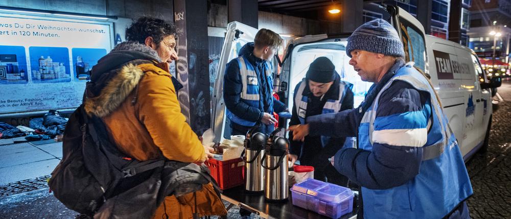Andre Ruschkowski, Marian, 19 und Michael, 39 verteilen Essen, bei der Suppenbus-Tour von Hertha BSC Fans am Alexanderplatz.