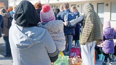 Geflüchtete aus der Ukraine stehen mit ihrem Gepäck vor den Gebäuden eines Flüchtlingsheims in Köln Worringen.