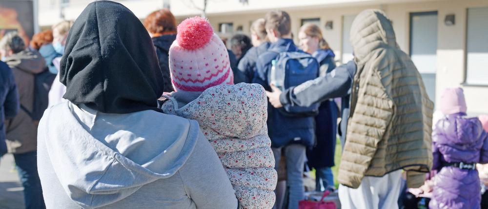 Geflüchtete aus der Ukraine stehen mit ihrem Gepäck vor den Gebäuden eines Flüchtlingsheims in Köln Worringen. 
