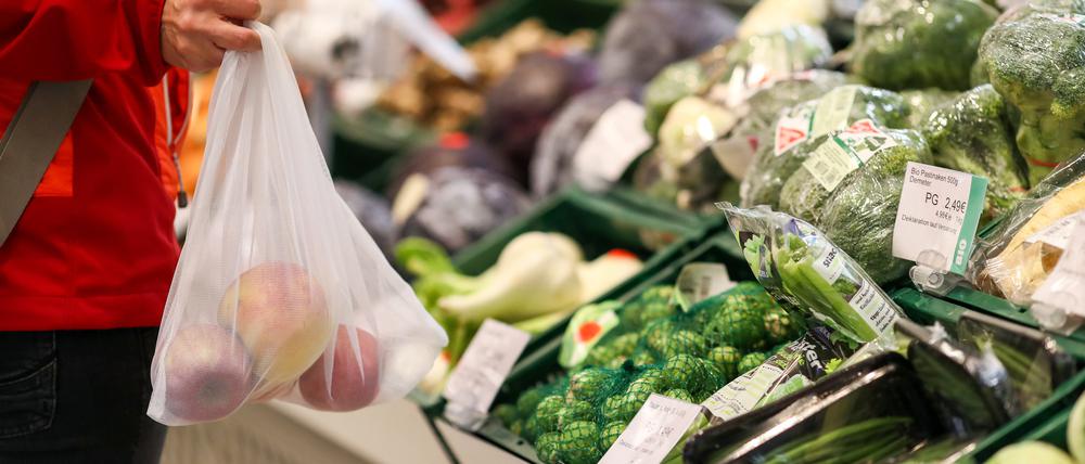 Eine Kundin steht mit einem Mehrweg-Einkaufsnetz in der Obst- und Gemüseabteilung in einem Supermarkt. Angesichts der Preisexplosion in Supermärkten und bei Discountern befürwortet die breite Mehrheit der Menschen in Deutschland einer Umfrage zufolge nun auch staatliche Eingriffe bei den Lebensmittelpreisen.