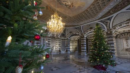 Zwei festlich geschmückte Weihnachtsbäume stehen im Grottensaal vom Neuen Palais.