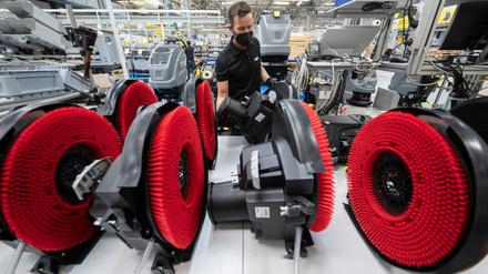 Ein Mitarbeiter eines Reinigungsgeräteherstellers nimmt in der Produktion den Bürstenkopf einer Scheuersaugmaschine von einer Ablage. Die deutschen Maschinenbauer beschäftigen mehr als eine Million Mitarbeitende.
