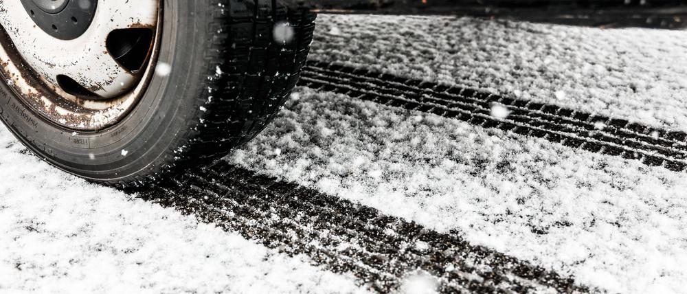 Ein Autoreifen auf einer verschneiten Straße. (Symbolbild)