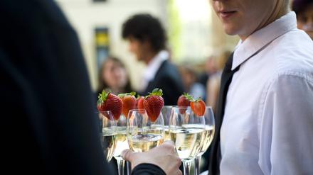 Gast nimmt vom gereichten Tablett ein Glas Sekt.