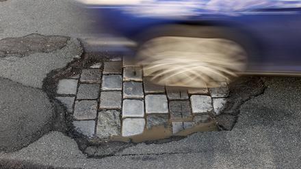  Ein Auto fährt über eine Straße mit Schlaglöchern. 