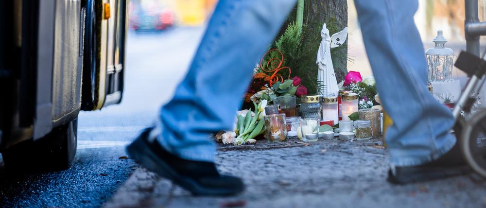 Blumen und Kerzen liegen nach einem Unfall mit einem Doppeldecker-Bus, bei dem eine Jugendliche gestorben ist, an der Bushaltestelle Stadtbad Lankwitz.