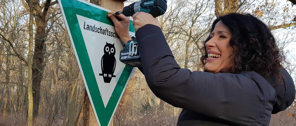 Umweltsenatorin Bettina Jarasch montiert das erste Schild im neuen Landschaftsschutzgebiet.