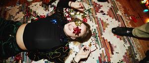 Laughing woman lying on floor with bows over eyes during holiday party with friends