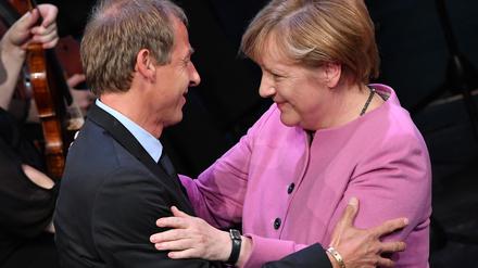 Der ehemalige Bundestrainer Jürgen Klinsmann und die frühere Bundeskanzlerin Angela Merkel (CDU) umarmen sich.