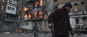 Ein Anwohner verlässt sein Wohnhaus, das nach einem Beschuss in Flammen steht.