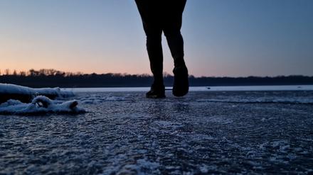 Ein Mann geht über den zugefrorenen Gördensee in Brandenburg.
