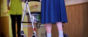 Eine ältere Dame geht mit ihrem Rollator über einen Flur.