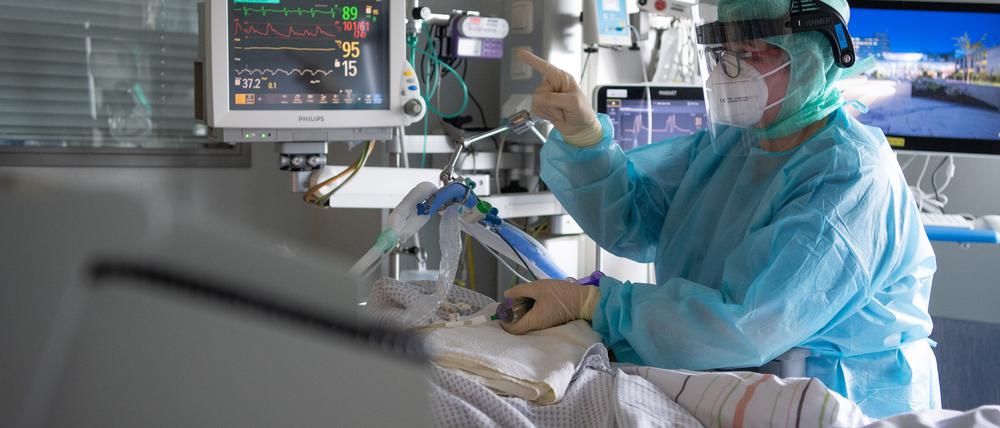 Eine Intensiv-Pflegerin versorgt einen schwer an Corona erkrankten Patienten auf der Intensivstation des Klinikums in Fulda.