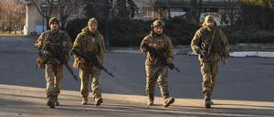 Ukrainische Soldaten gehen eine Straße entlang, in der schwere Kämpfe mit der russischen Armee stattfanden.