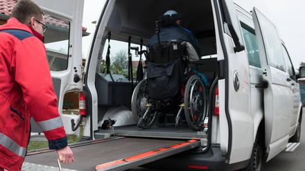 Ein Mann vom DRK-Fahrdienst schiebt Rollstuhlfahrer über eine Rampe in den Transporter. Fahrdienst *** A man from the DRK transport service pushes wheelchair users over a ramp into the transporter transport service 
