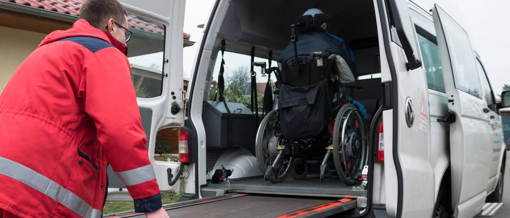 Ein Mann vom DRK-Fahrdienst schiebt Rollstuhlfahrer über eine Rampe in den Transporter. Fahrdienst *** A man from the DRK transport service pushes wheelchair users over a ramp into the transporter transport service