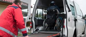 Ein Mann vom DRK-Fahrdienst schiebt Rollstuhlfahrer über eine Rampe in den Transporter. Fahrdienst *** A man from the DRK transport service pushes wheelchair users over a ramp into the transporter transport service 