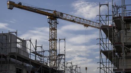 Ein Turmdrehkran ragt in den Himmel auf einer Baustelle zwischen neu errichteten Wohnhäusern. 