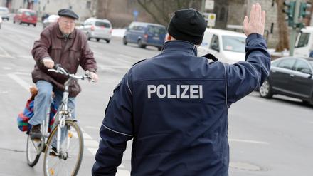 Ein Polizist stoppt einen Fahrradfahrer an der Kaiser-Wilhelm-Straße.