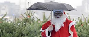 Ein Weihnachtsmann schützt sich am 10.12.2009 im Hamburger Hafen an Deck des Hafenrundfahrtsschiffes „Hamburg“ mit einem Schirm gegen den Dauerregen.