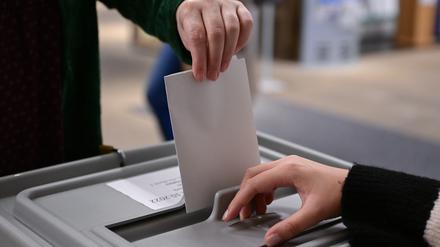 Ein Wähler steckt seinen Wahlzettel in eine Urne. 