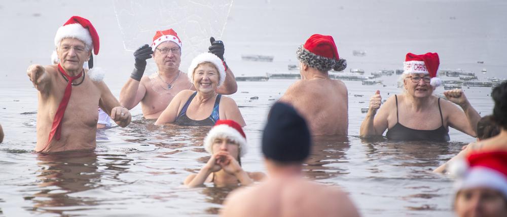 Mitglieder des Vereins „Berliner Seehunde“ baden beim Weihnachtsbaden im Orankesee zwischen Eisschollen.