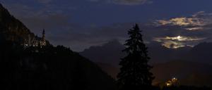 Im Dunklen steht das Schloss Neuschwanstein vor dem zunehmenden Mond und dem Schloss Hohenschwangau (Symbolbild).