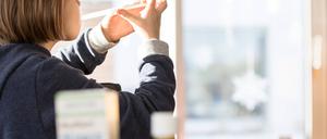 Auf einem Tisch stehen Fieber- und Schmerzmittelsaft für Kinder, im Hintergrund sitzt ein krankes Kind das den Schmerzsaft gegen Fieber sowie Schmerzen einnimmt. Aktuell herrscht in Deutschland ein Mangel an Medikamenten wegen Lieferengpässen. 