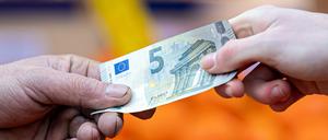 ARCHIV - 29.01.2022, Niedersachsen, Hannover: Ein Kunde bezahlt seinen Einkauf an einem Stand auf einem Wochenmarkt mit einem Fünf-Euro-Schein (gestellte Szene). Bezahlen ohne Scheine und Münzen gewinnt für Verbraucher im Euroraum nach Einschätzung der Europäischen Zentralbank (EZB) zunehmend an Bedeutung. (zu dpa «EZB-Studie: Bargeld verliert beim Bezahlen an Bedeutung») Foto: Moritz Frankenberg/dpa +++ dpa-Bildfunk +++