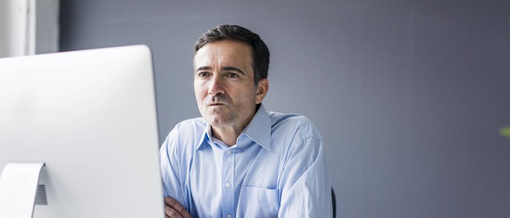 Serious businessman sitting at desk in office looking at computer screen model released Symbolfoto property released PUBLICATIONxINxGERxSUIxAUTxHUNxONLY JOSF02861
