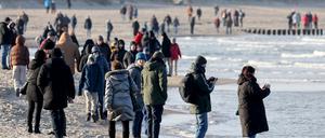 Spaziergänger sind am Ostseestrand unterwegs. 