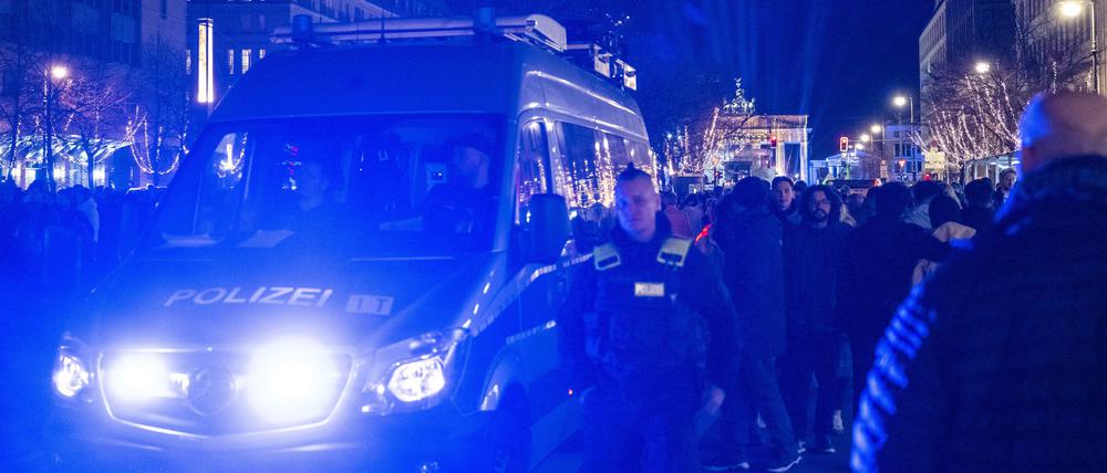 Ein Polizeiauto fährt vor dem Brandenburger Tor mit Blaulicht durch die Menschenmenge.