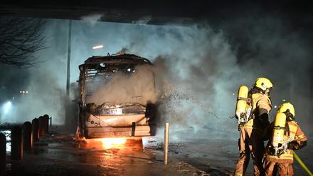 Feuerwehrmänner löschen in der Silvesternacht an der Berliner Sonnenallee einen Reisebus, der von Unbekannten angezündet worden war.