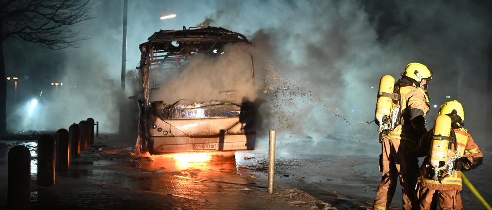 Feuerwehrmänner löschen in der Silvesternacht an der Berliner Sonnenallee einen Reisebus, der von Unbekannten angezündet worden war.