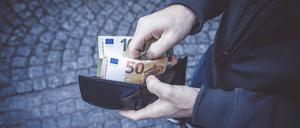 Ein Mann öffnet seine Geldbörse und hält 150 Euro Geldscheine in seiner Hand. Mann mit Bargeld in der Hand