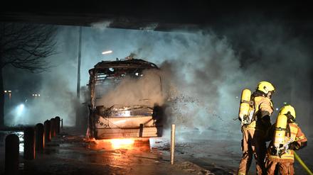 Feuerwehrmänner löschen an der Sonnenallee einen Reisebus, der von Unbekannten angezündet worden war. 