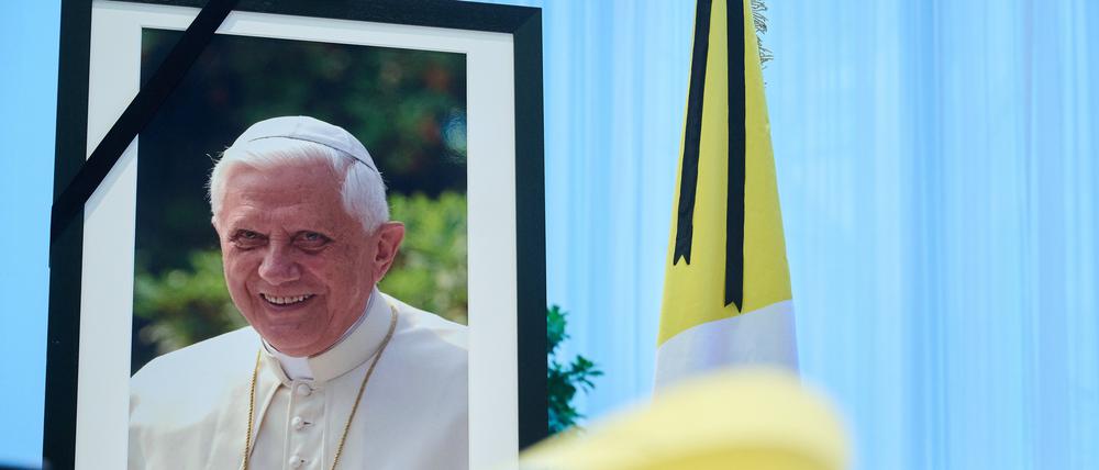 Das Kondolenzbuch für den verstorbenen emeritierten Papst Benedikt XVI. liegt auf einem Tisch vor einem Bild des Verstorbenen. 