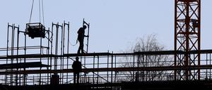 Handwerker arbeiten am Neubau eines Mehrfamilienhauses an einem Baugerüst. 