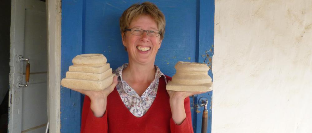 Gunvor Lindström von der Eurasien-Abteilung des Deutschen Archäologischen Instituts (DAI) am Grabungshaus in Torboluk (Tadschikistan) mit zwei baktrischen Miniaturaltären, die sie dort ausgegraben hat.