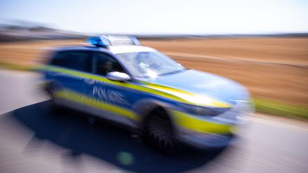 Ein Polizeiauto fährt über eine Dorfstraße.