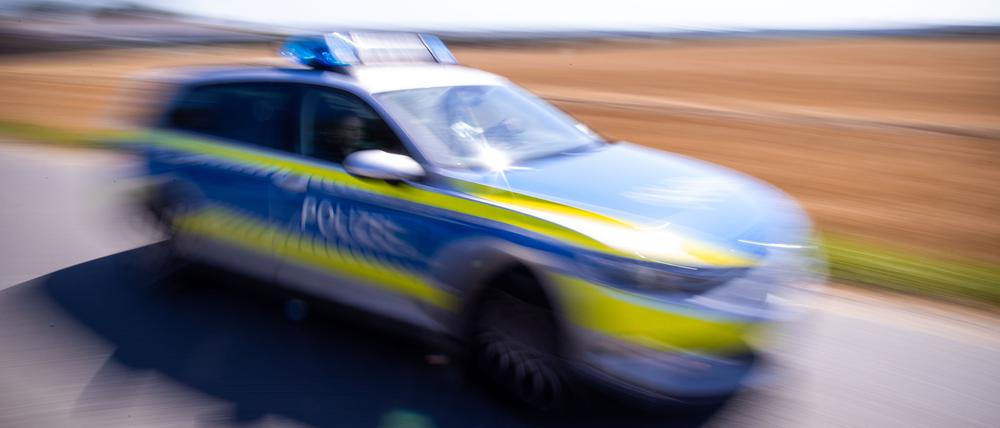 Ein Polizeiauto fährt über eine Dorfstraße.