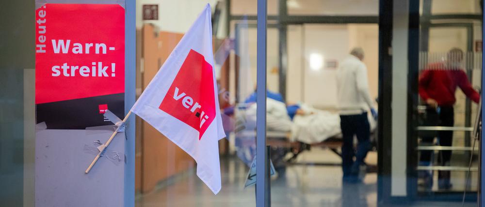 Eine Verdi-Fahne sowie ein Plakat hängen bei einem Streik von Beschäftigten der Berliner Charité am Bettenhochhaus.
