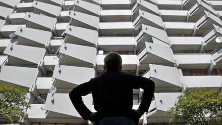 Ein Junge vor einem Wohnhochhaus mit Balkonen und Satellitenschüsseln.