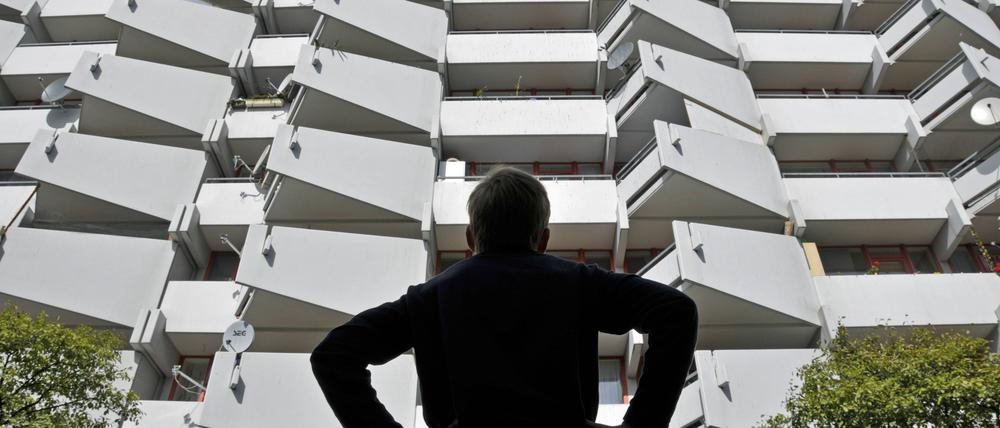 Ein Junge vor einem Wohnhochhaus mit Balkonen und Satellitenschüsseln.